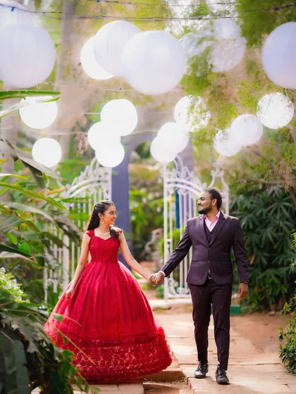 A wide shot capturing the magical ambiance of a pre-wedding shoot with hanging lanterns and lush greenery.