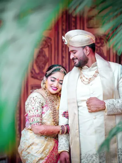 An elegant portrait of the couple, framed by natural elements. The soft lighting and their gentle interaction create a timeless and romantic wedding photograph.