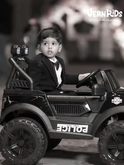 The little boss. A classic black tuxedo with a burgundy bow tie is a timeless choice for a milestone birthday, making him look sharp and feel important.