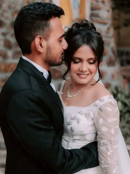 A romantic embrace. The groom holds his bride close, and her soft, glowing makeup looks flawless.