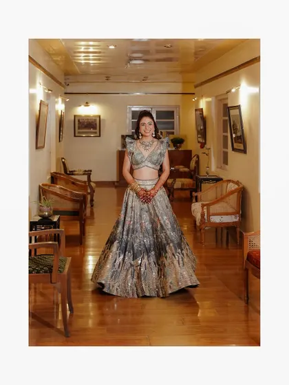A wide shot of the bride in her stunning lehenga, standing in the elegant corridor of the heritage hotel.