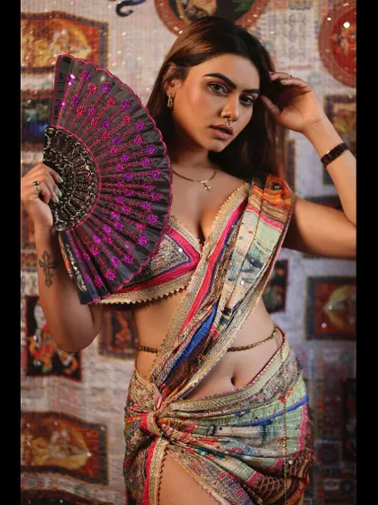 A glamorous and modern take on ethnic wear. The model holds a fan, adding a touch of drama and flair to her intricately designed saree.