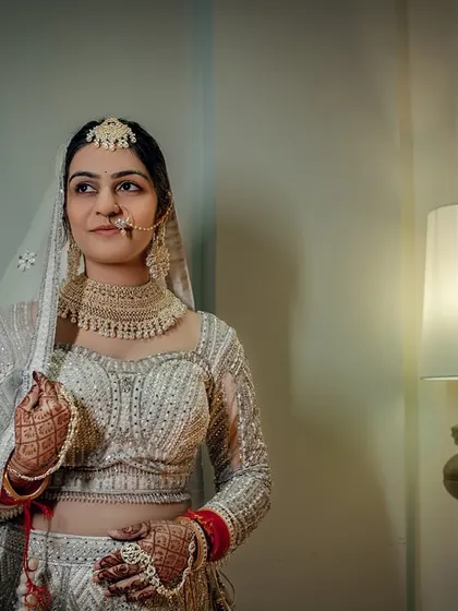 A close-up of the bride in her white lehenga, her expression a mix of anticipation and happiness.