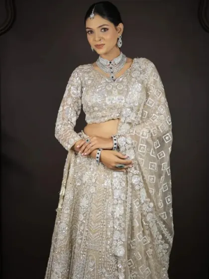 A full front view of the ivory lehenga with geometric embroidery, paired with a diamond and emerald jewellery set.