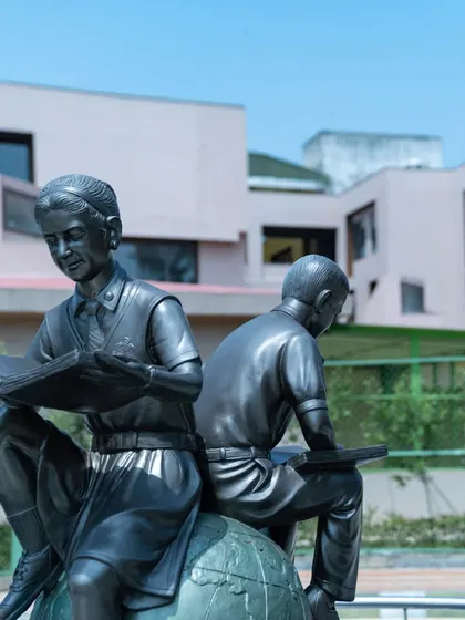 The sculpture seen from a different angle, with the modern school building in the background. We carefully site these features to create memorable focal points within the campus landscape.