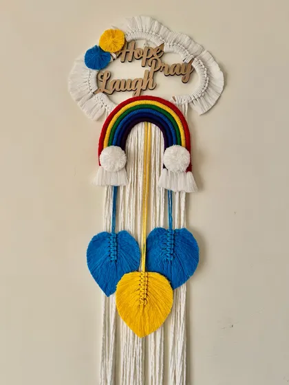 A full view of the "Hope Pray Laugh" name hanging, a positive and uplifting piece of decor.