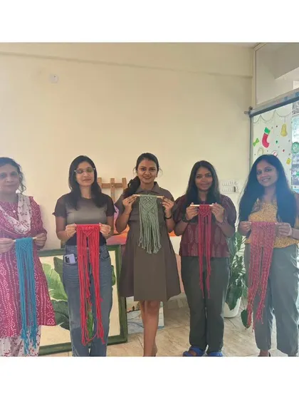 A group of participants with their finished macrame wall hangings. Each piece has its own unique style and color combination.