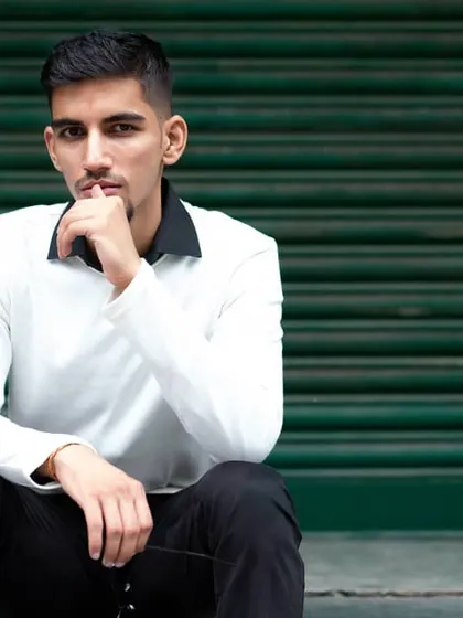 A modern urban portrait of Karan Lakhanpal against a green metal shutter. The simple background helps the subject stand out.
