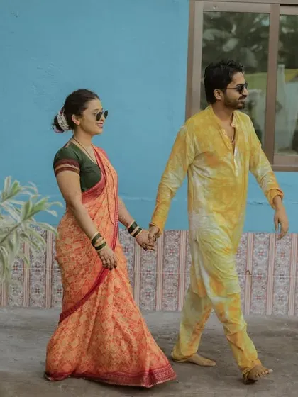 A cool, candid shot of the couple walking hand-in-hand after their Haldi ceremony. The contrast with the blue wall makes for a great photo.