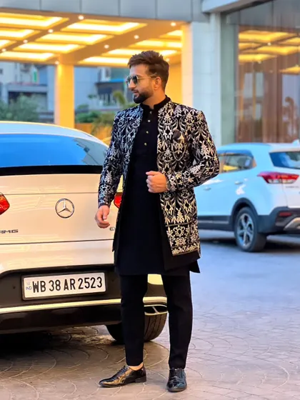 This black and silver Indo-Western sherwani is a perfect example of our fusion wear. The detailed embroidery on the jacket, paired with a classic black kurta, offers a sophisticated look for a reception or sangeet.