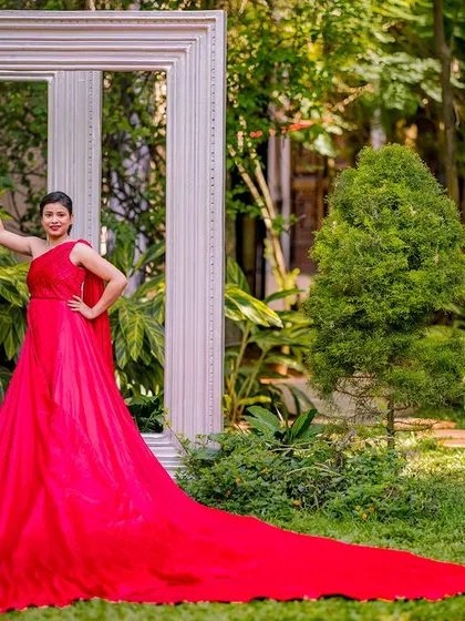 A stylish and confident pose with the giant frame props. The red gown's long train extends across the lawn, adding a touch of glamour and drama to the portrait.