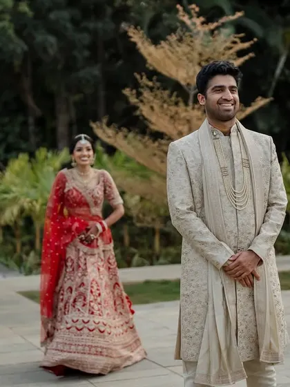 A regal portrait of the couple in their stunning red and cream wedding attire. We use architectural elements like staircases to add a touch of grandeur to our compositions.