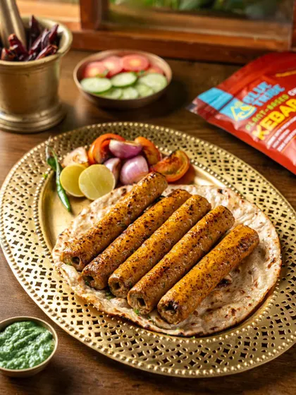 Plant-based seekh kebabs from Blue Tribe, styled in a traditional way on a brass platter with roti and chutney. This presentation makes the modern product feel familiar and accessible.