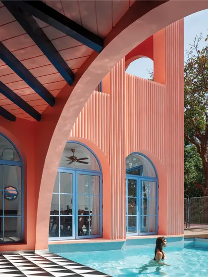 The poolside at Baia Villas is a study in contrasts. The vibrant peach facade and blue window frames are balanced by the classic black-and-white checkered flooring, creating a space that feels both energetic and timeless.
