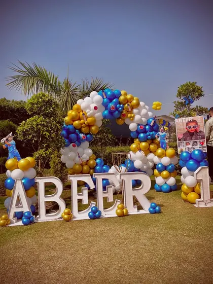 A wide shot of the complete outdoor setup, including the large 'ABEER' letters, balloon arch, and themed props.