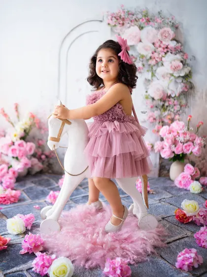A classic rocking horse photo, set against a beautiful backdrop of pink and white flowers.