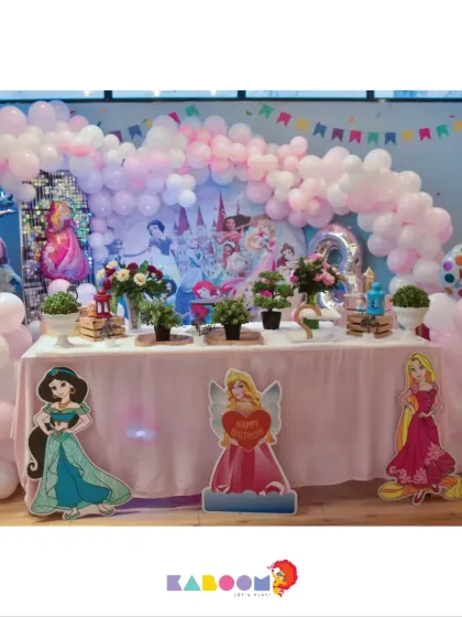 A royal celebration fit for a princess! This party setup is adorned with soft pink balloons, a castle backdrop, and cutouts of favorite Disney princesses like Jasmine and Rapunzel.