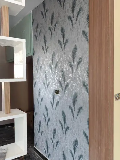 A wall with a silver-grey wallpaper featuring a feather pattern, adding a touch of modern elegance.
