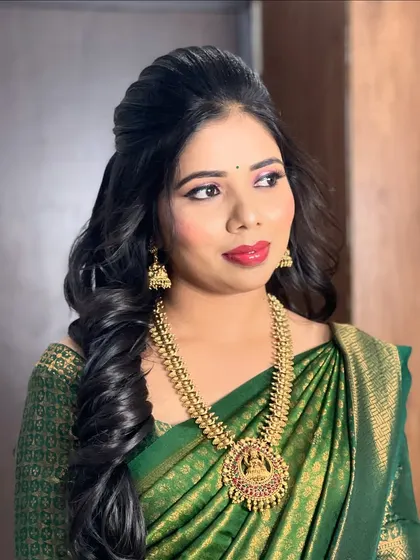 Rakhi's engagement look, featuring a beautiful green silk saree. I gave her a classic South Indian makeup look with a bold red lip and soft, romantic curls.