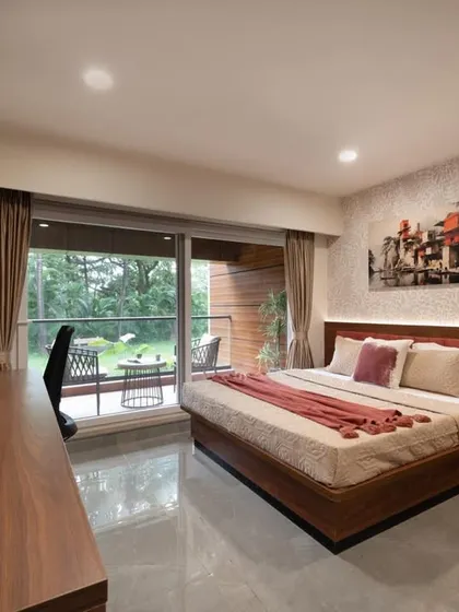 This guest bedroom is designed with warm tones, featuring a custom wood and terracotta-colored headboard. The room opens onto a private balcony, offering guests a personal space to enjoy the outdoor scenery.