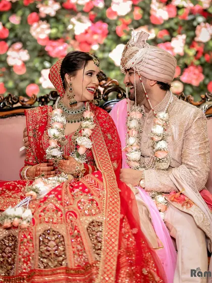 A joyful and candid portrait of the couple seated on their wedding stage, sharing a laugh and looking deeply into each other's eyes.