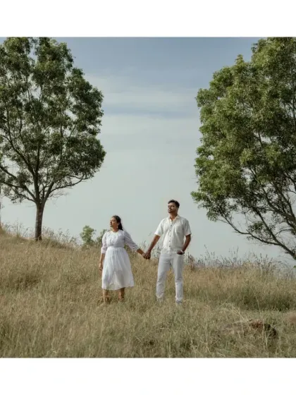 A couple walks hand-in-hand through a field, framed by two trees. A simple, classic, and beautiful shot that symbolizes their path together.