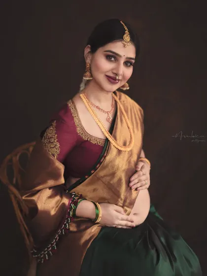 A classic seated portrait that radiates elegance and grace. The rich colors of the saree and the warm, moody lighting come together to create a photograph that feels like a classic painting.