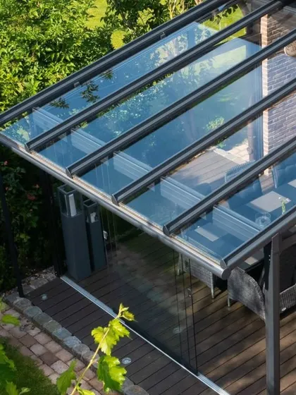 An aerial view of a glass enclosure we built for a patio. The structure is designed to fit the exact dimensions of the space, creating a seamless, fully-enclosed sunroom with clear views of the surrounding garden.