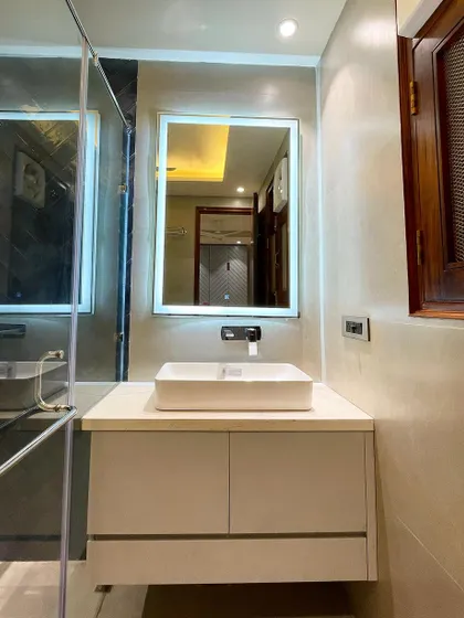 The vanity area in this bathroom features a simple, clean design with a white countertop and basin, complemented by a large backlit mirror that provides excellent task lighting.