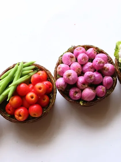A collection of vegetable baskets, including tomatoes, beans, onions, and cauliflower.