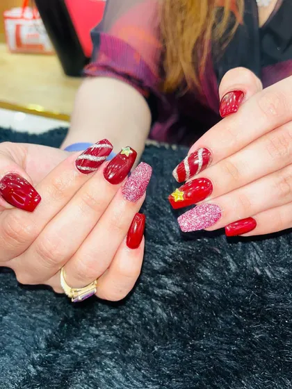 Another angle of this fun and festive Christmas manicure. The combination of glossy red, pink glitter, and candy cane stripes makes for a cheerful holiday look.
