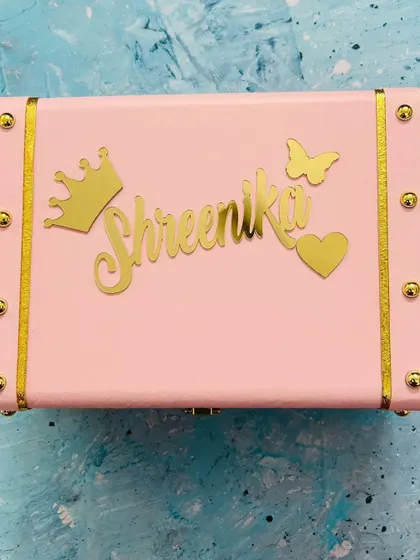 A lovely pink trunk box customized with a name, crown, and butterfly, perfect for storing precious items.