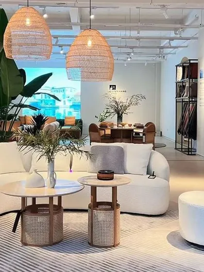 This showroom view captures the essence of the Siena collection's tropical sophistication. The combination of the white Poet Sofa, rattan lighting, and Siena tables creates a complete and harmonious living environment.