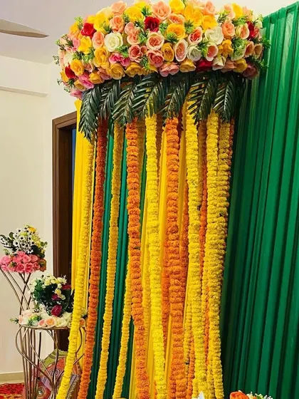 A close-up of a floral canopy made with marigold strings and a dense arrangement of roses on top.