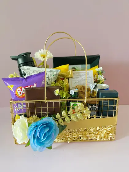 A metal hamper basket curated for Rakhi. It's filled with gifts for a brother, including a wallet, snacks, and grooming items.