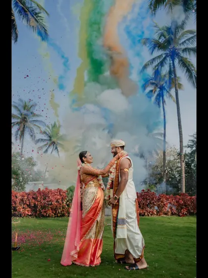 A colorful varmaala exchange against a backdrop of palm trees and smoke bombs. We love incorporating creative elements to make your wedding photos unique and spectacular.