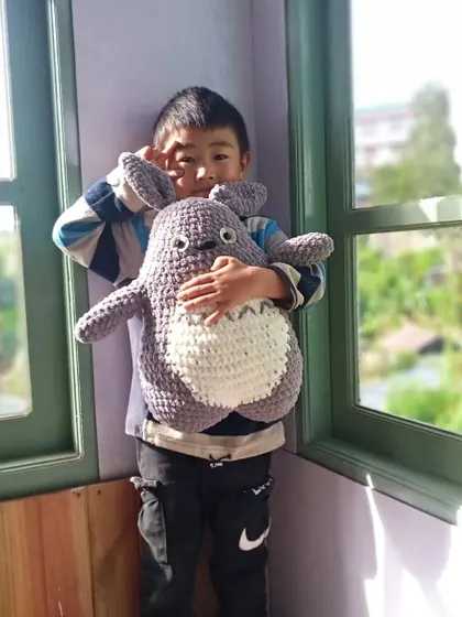 Seeing the joy my creations bring is the best reward. Here is a happy customer with a large, cuddly Totoro plushie I made, perfect for fans of Studio Ghibli.