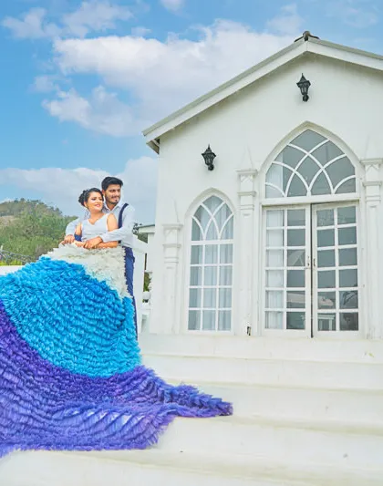 A stunning ruffled, multi-toned gown from our collection cascades down the steps of our white villa, making for an unforgettable pre-wedding picture.
