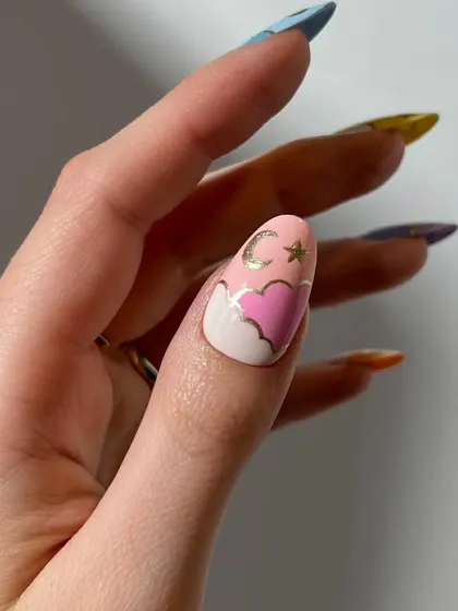A close-up of the thumb nail from the celestial set, showing a pink heart-shaped cloud with a gold moon and stars.