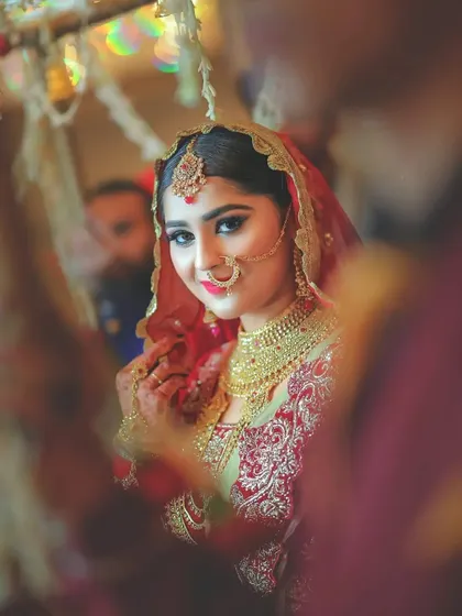 A lovely shot of the bride looking into a mirror, capturing her reflection and her beautiful smile on the wedding day.