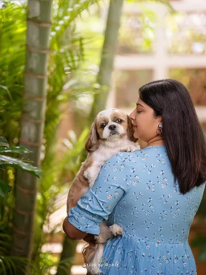 Your home is the best location for a photoshoot because it's where your memories are made. Here, a woman shares a quiet moment with her Shih Tzu in their beautiful, green-filled home.