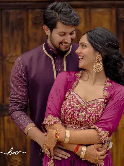 A happy and romantic portrait of the couple, their purple and magenta outfits complementing each other perfectly for a pre-wedding event.