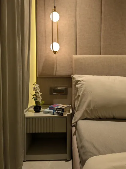 This bedside setup features a minimalist table with a fluted drawer front, paired with a stylish hanging pendant light, freeing up surface space.