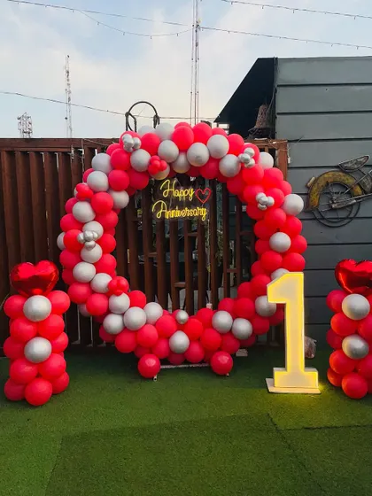 A fun and festive first-anniversary rooftop party. The red and silver circular balloon arch is accented with heart-shaped foil balloons.