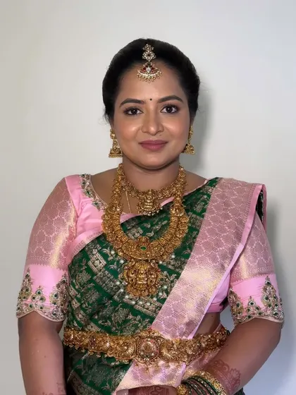 A beautiful client ready for a wedding event. Her makeup is classic South Indian, with an emphasis on the eyes and glowing skin, perfectly matching her green and pink Kanjivaram saree.