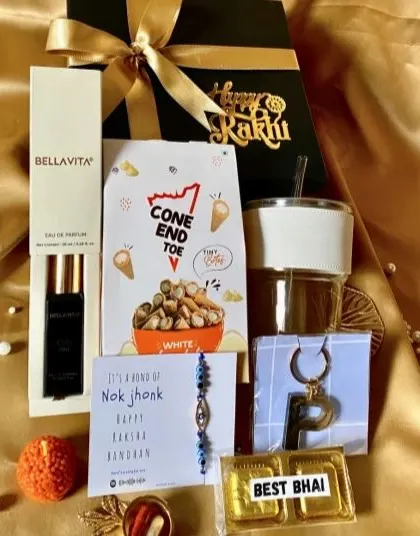 A premium Rakhi hamper featuring a glass sipper, Bellavita perfume, snacks, a keychain, and a 'Best Bhai' chocolate.