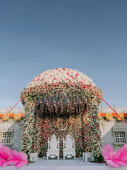 A spectacular floral mandap designed to make a statement. The dome is completely covered in a dense arrangement of white and pink roses, creating a breathtaking floral masterpiece for a truly luxurious wedding.