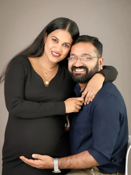A happy and relaxed couple portrait. The mom-to-be leans into her partner with a bright smile, showing the comfort and love they share.