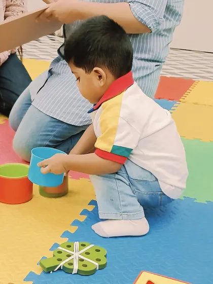 A child engages in a sorting and stacking game with colorful cups, an activity that teaches colors, sizes, and basic counting.