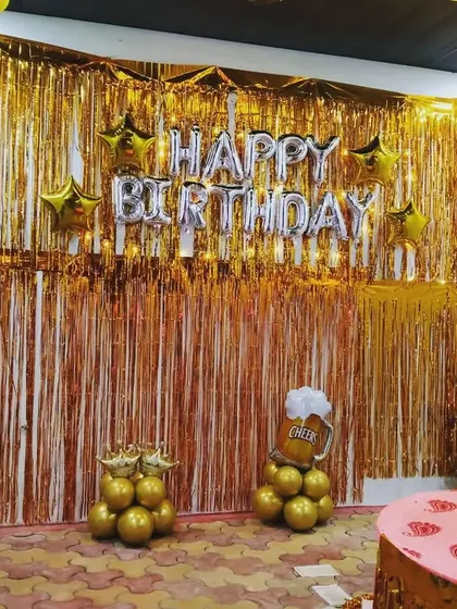 A fun and unique birthday theme for an adult party. This setup features a golden shimmer curtain and balloon pillars designed to look like beer and whiskey bottles.